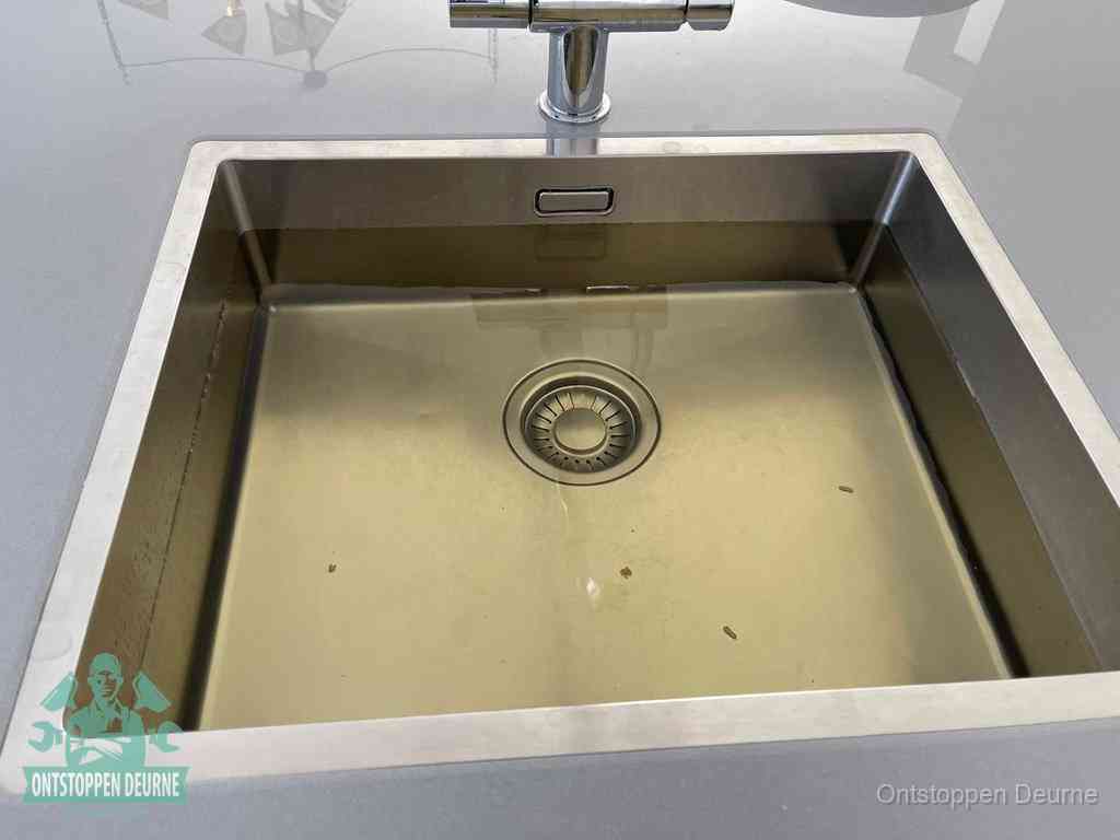 Stilstaand water in een rvs spoelbak dat niet wegloopt, een duidelijk signaal van een gootsteenverstopping in Deurne