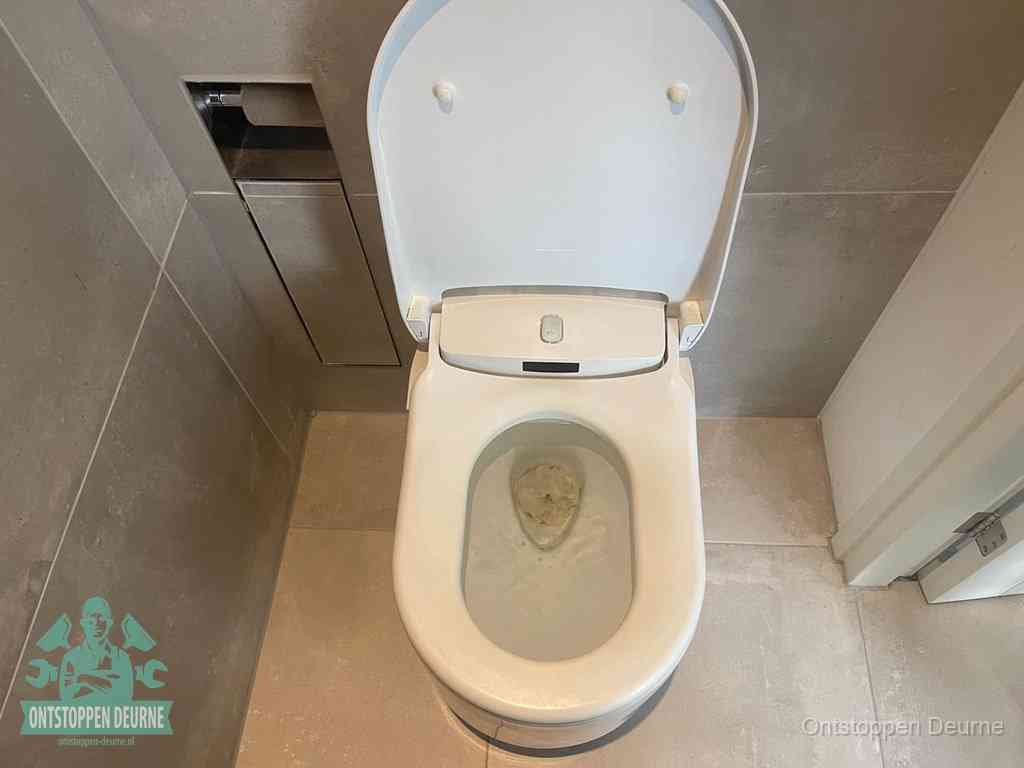 Een wit hangtoilet waarin een prop wc-papier op het water blijft drijven, een duidelijk signaal van een verstopte wc in Deurne