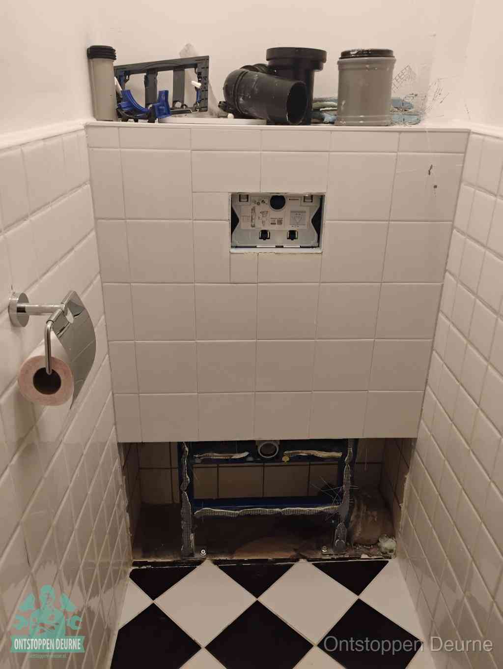 Een toiletruimte waar het hangtoilet en de inbouwreservoir-onderdelen zijn vrijgelegd voor onderhoud, periodiek nazicht voorkomt een wc-verstopping in Deurne