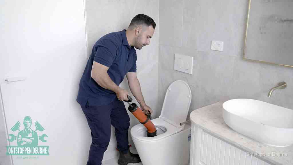 Een monteur gebruikt een handmatige perspomp (toiletontstopper) op een wandcloset tijdens het professioneel wc ontstoppen in Deurne